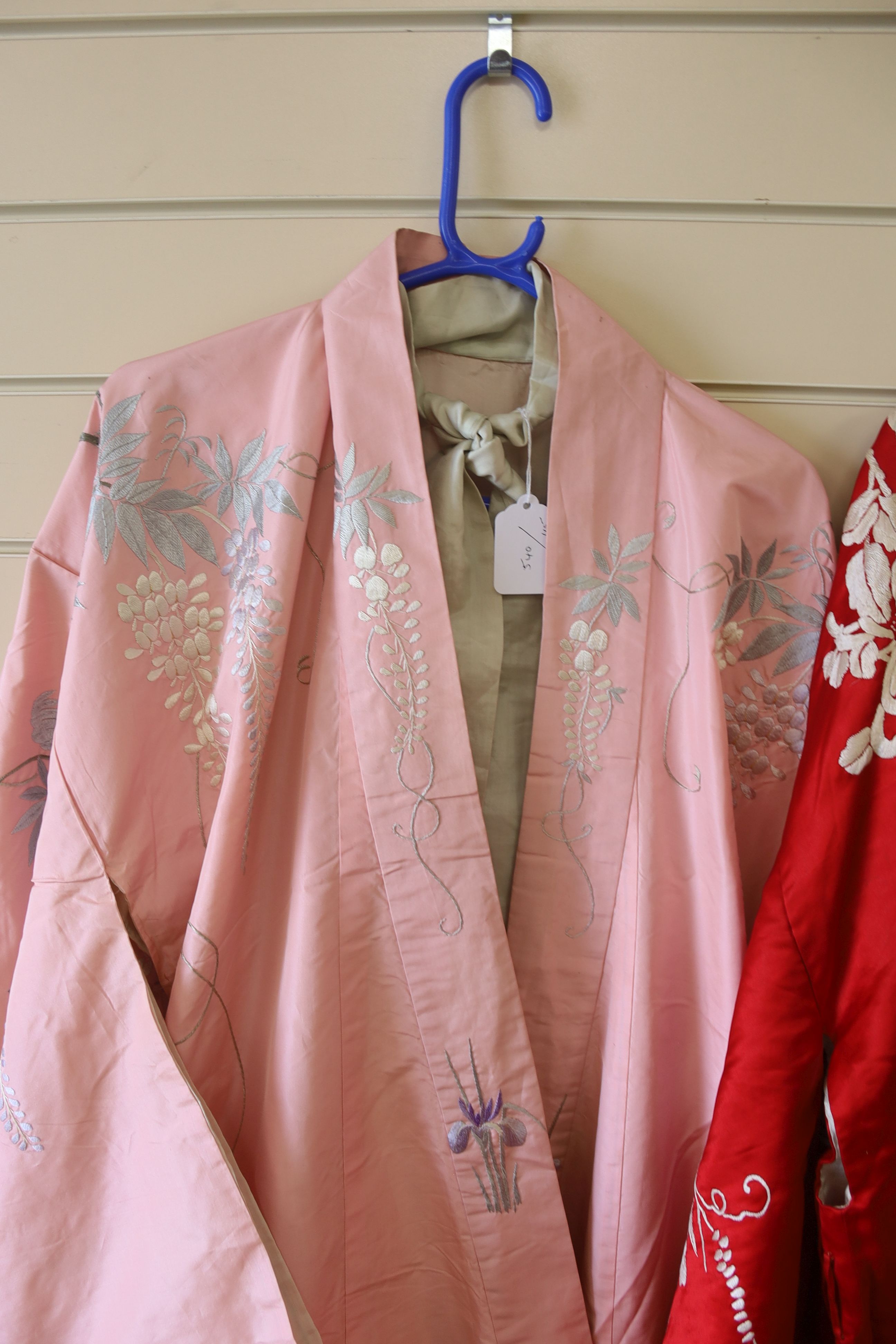 A pink silk Japanese kimono embroidered with wisteria and irises and butterflies, length 140cm, together with a red kimono embroidered with white wisteria and carnations